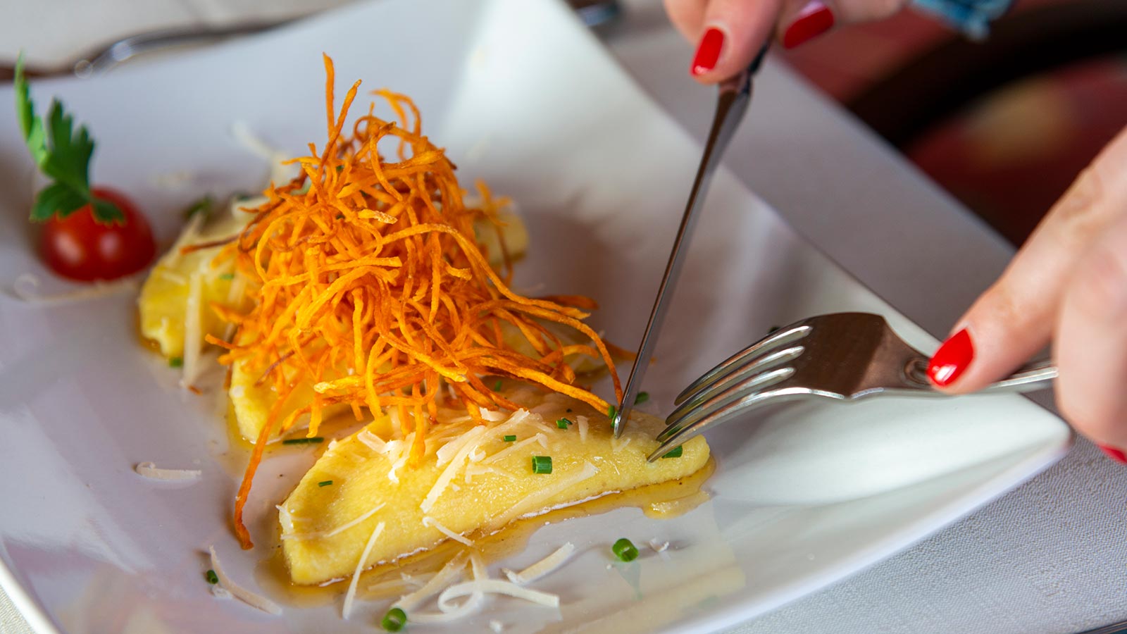 Dettaglio di una mano mentre taglia un raviolo nel ristorante dell'Hotel Grissianer Hof